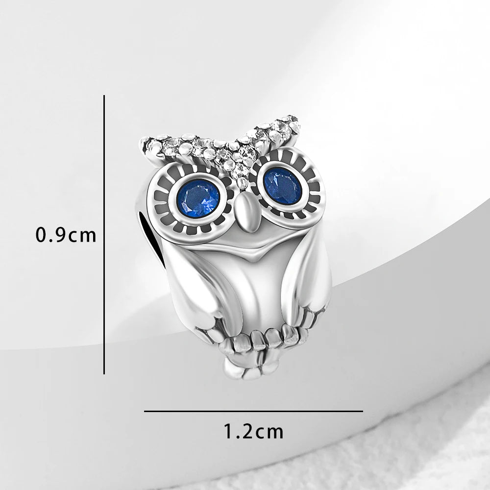 Silver owl-shaped ring with blue gemstones and measurements on a white background
