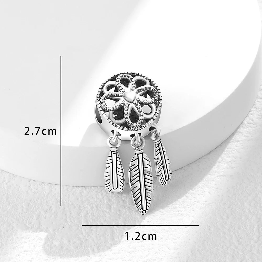 Silver charm with intricate design and feather details on a white background